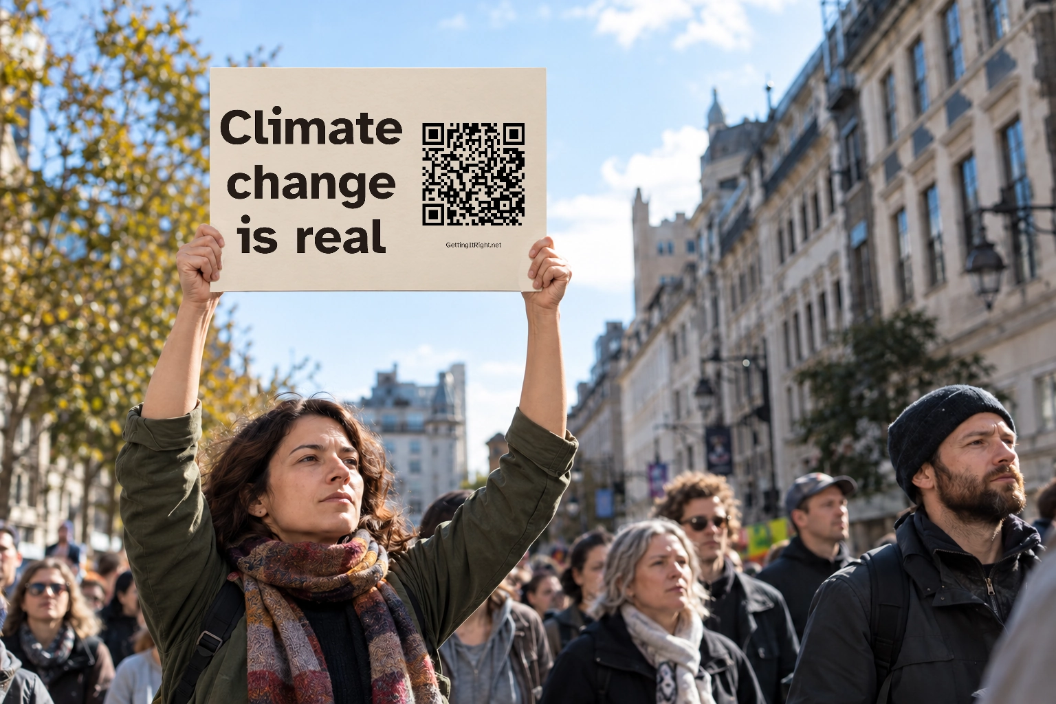 A person holds the actual Climate change is real sign overhead in an illustrative urban public gathering.